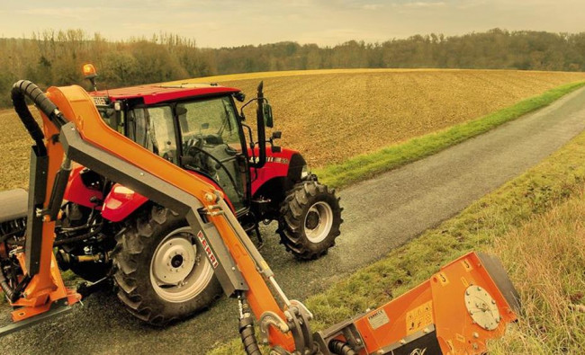 Traktorius Case IH Farmall C serijos skuta žolę šalia kelio